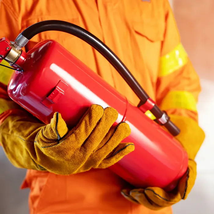 Worker in coveralls holding a fire extinguisher